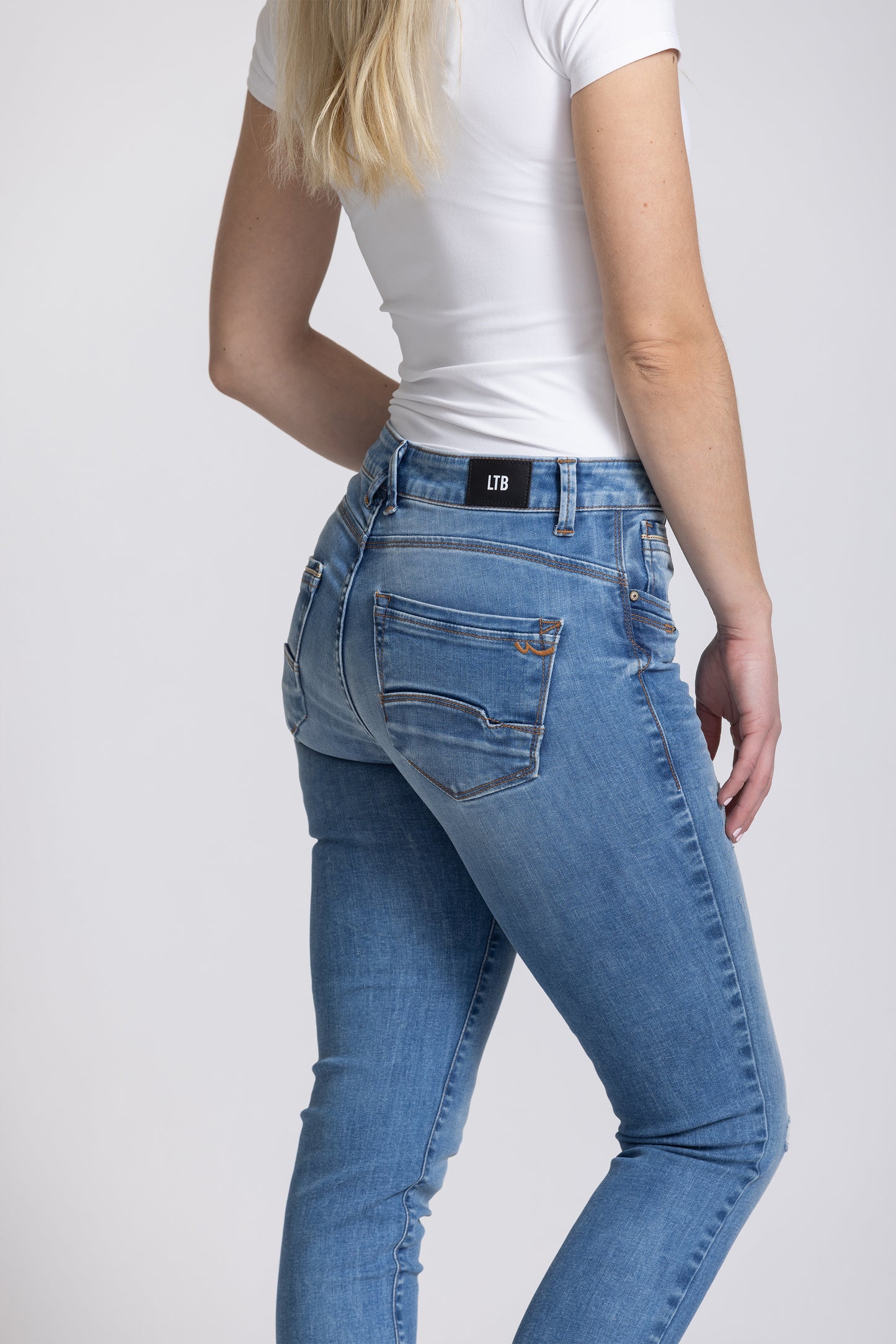 Person wearing blue jeans and a white t-shirt on a plain background
