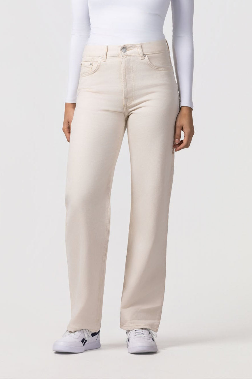 Person wearing a white long-sleeve top and beige pants on a white background