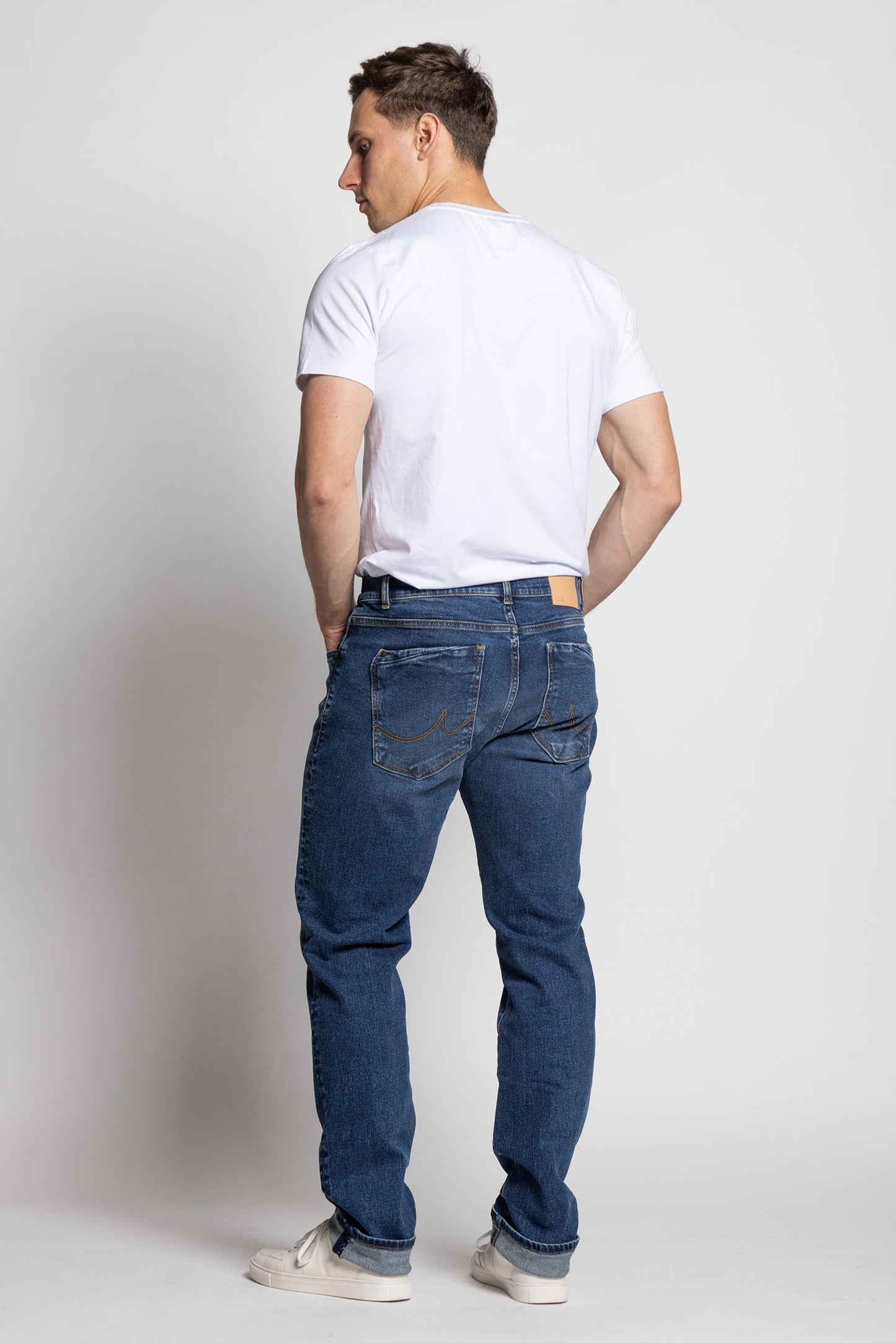 Man wearing blue jeans and a white t-shirt on a plain background