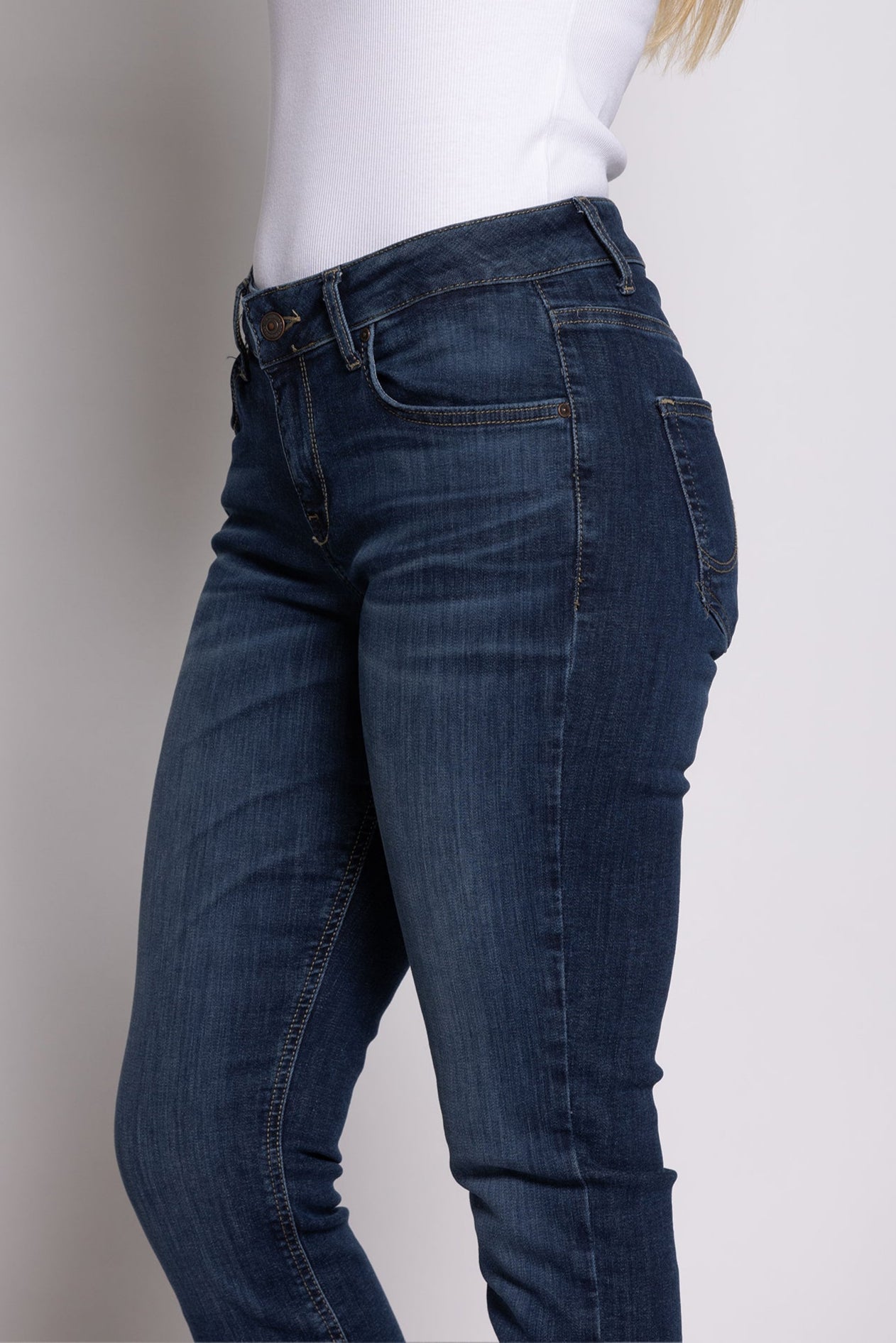 Women wearing a white t-shirt and blue jeans on a plain background