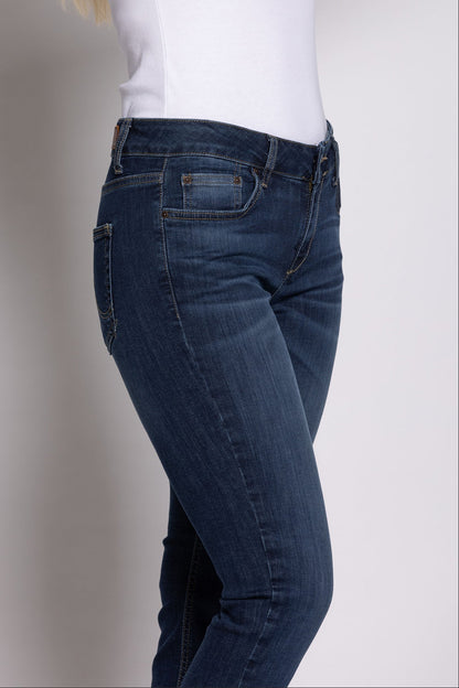 Person wearing blue jeans and a white top against a plain background