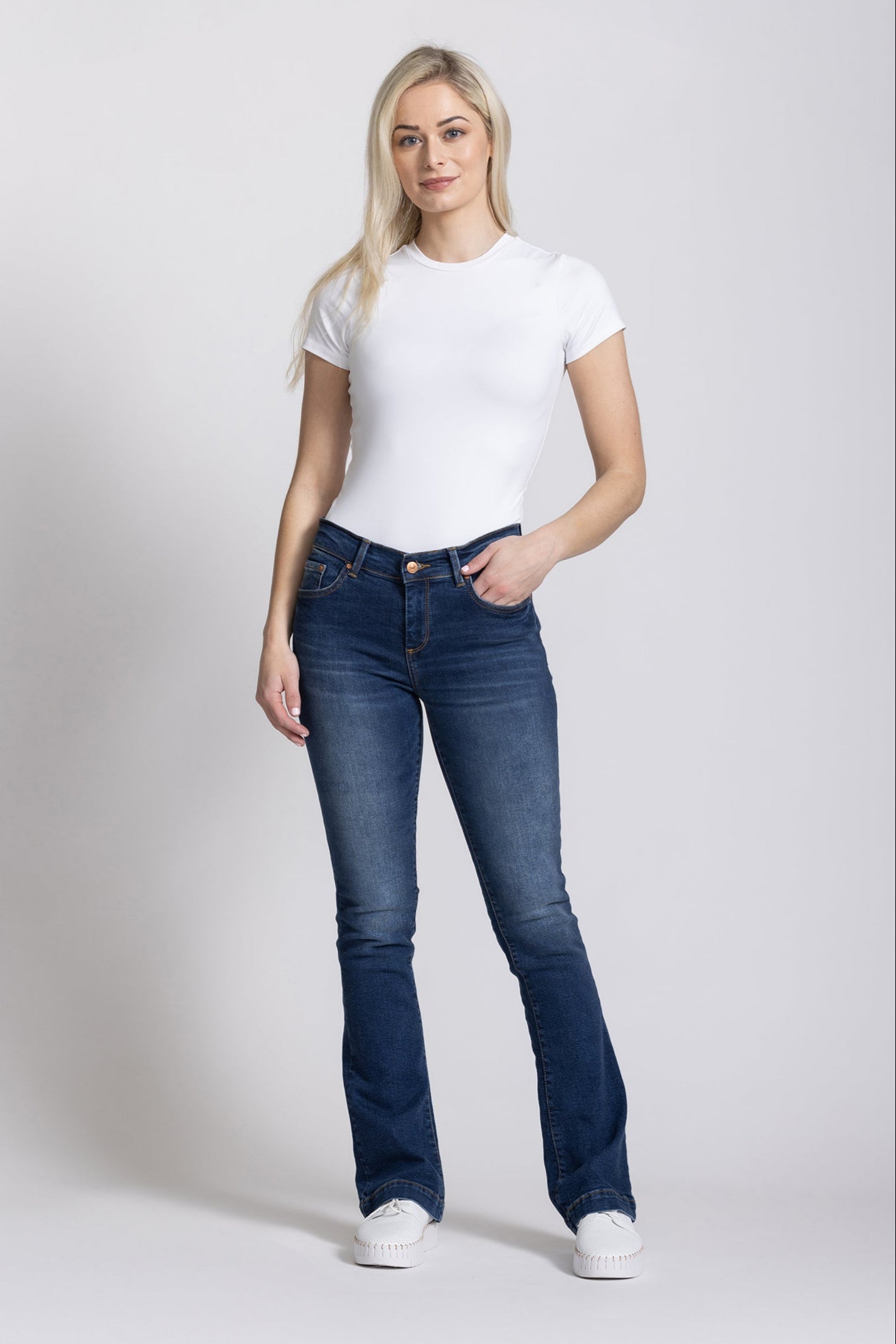 Woman wearing a white t-shirt and blue jeans on a white background