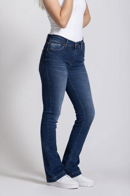 Woman wearing blue jeans and a white t-shirt on a plain background