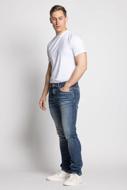 Man wearing a white t-shirt and blue jeans on a plain background
