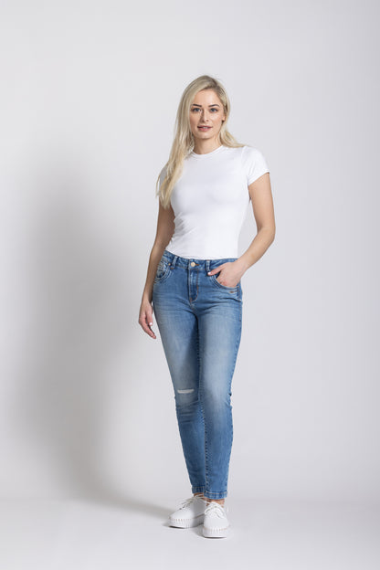 Woman wearing a white t-shirt and blue jeans on a plain background