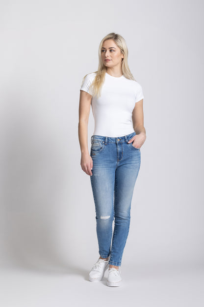Woman wearing a white t-shirt and blue jeans on a plain background