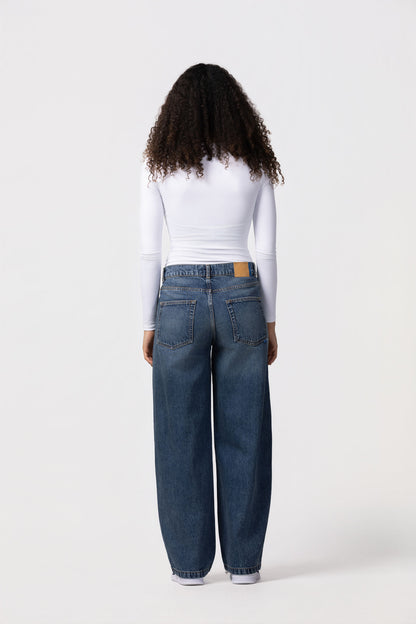 Person wearing blue jeans and a white long-sleeve shirt on a white background