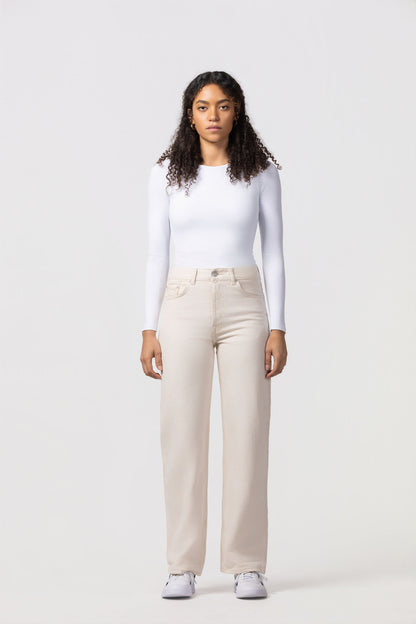 Woman wearing a white long-sleeve top and beige pants on a white background