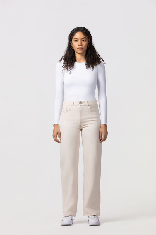 Woman wearing a white long-sleeve top and beige pants on a white background