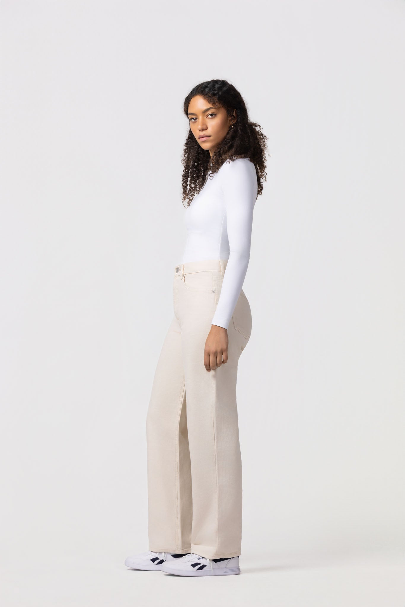 Person wearing a white long-sleeve top and beige wide-leg pants on a white background