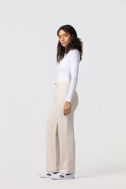 Person wearing a white long-sleeve top and beige wide-leg pants on a white background
