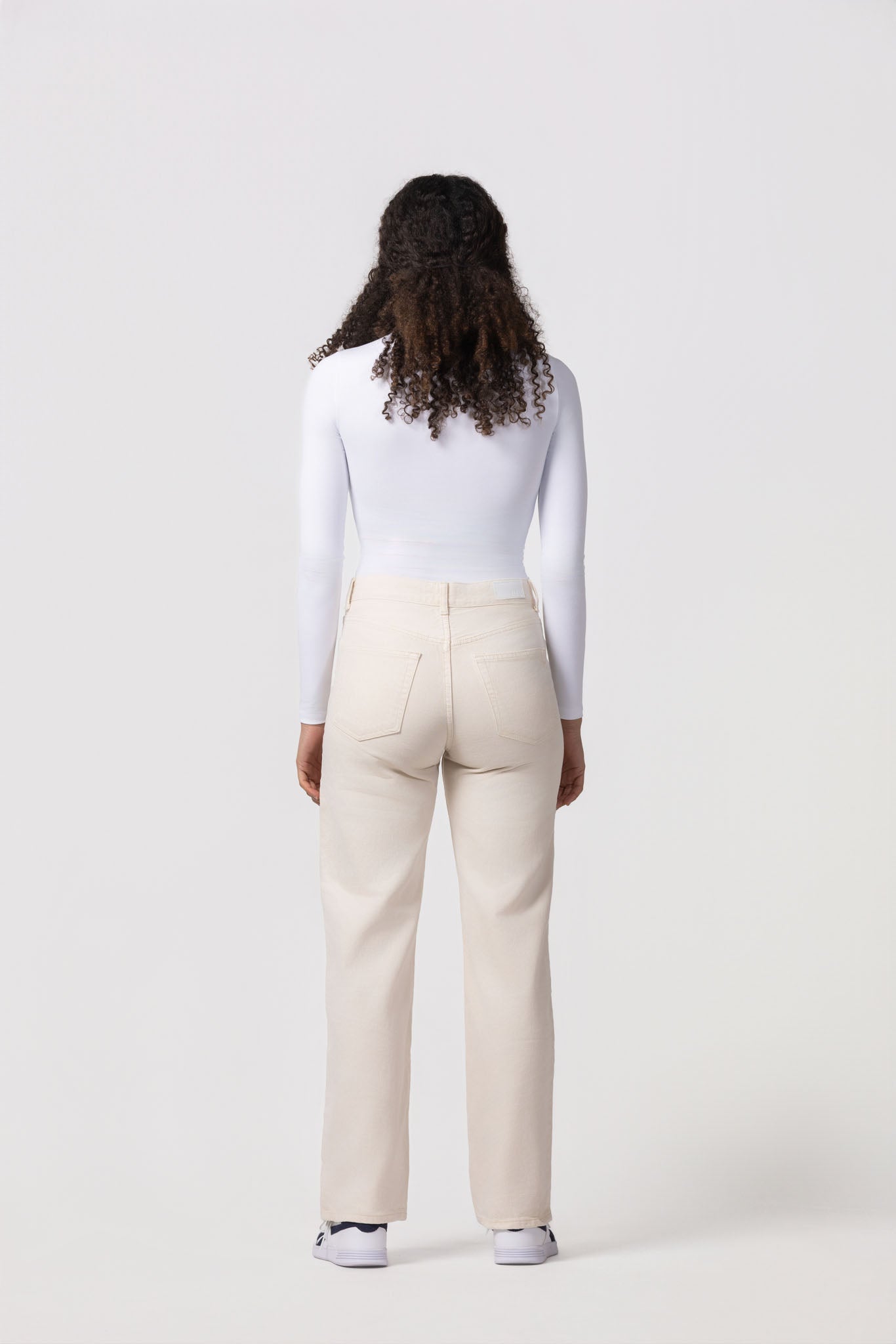 Person wearing a white top and beige pants on a white background