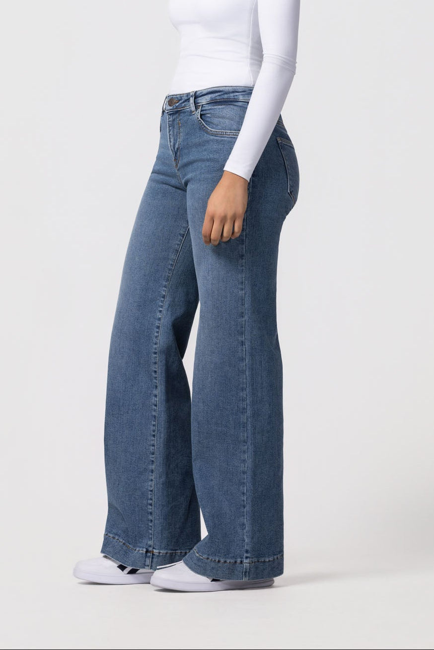 Woman wearing blue jeans and a white top on a white background
