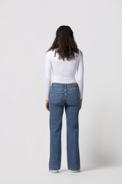 Person wearing blue jeans and a white top on a white background