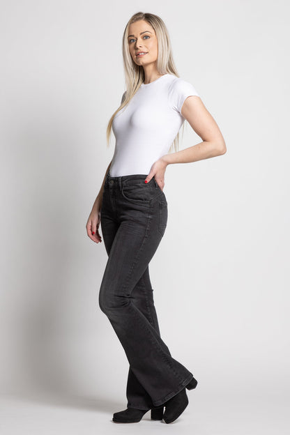Woman wearing a white t-shirt and dark pants on a plain background