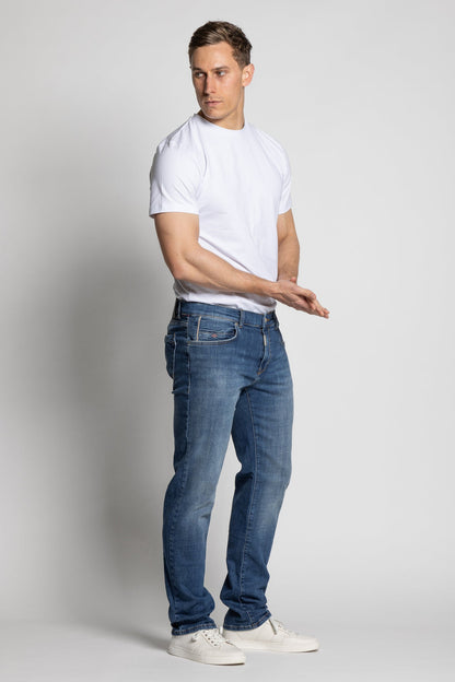 Man wearing a white t-shirt and blue jeans on a plain background