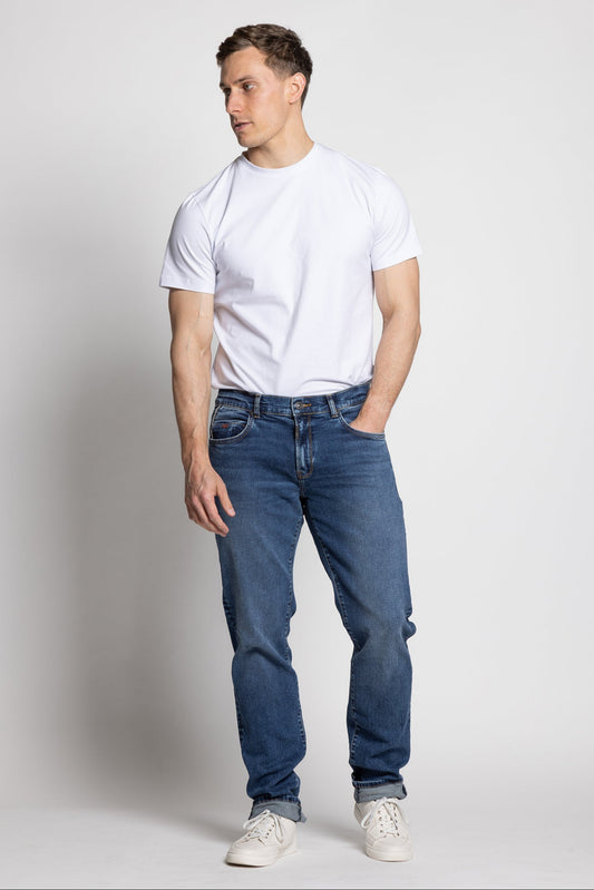 Man wearing a white t-shirt and blue jeans on a plain background