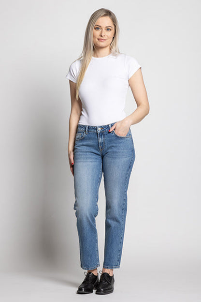 Woman wearing a white t-shirt and blue jeans on a plain background