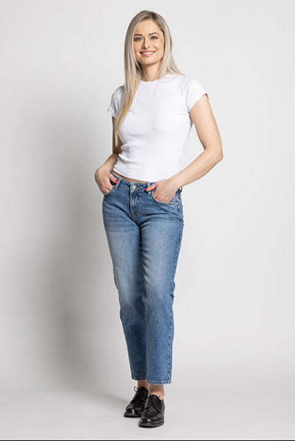 Woman wearing a white t-shirt and blue jeans on a plain background